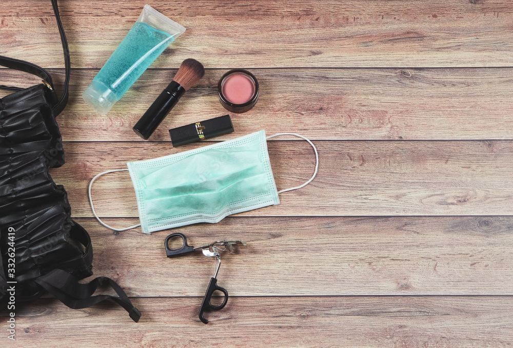 Top view or flat lay of woman's bag accessories with hygienic mask and sanitizer gel on wooden background , Protection from COVID-19 or Coronavirus concept. Top view or flat lay of woman's bag accessories with hygienic mask and sanitizer gel on wooden background , Protection from COVID-19 or Coronavirus concept.