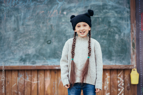 Little girl in a hat posing on the background of the school blackboard © teksomolika