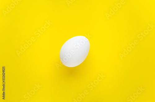 One white egg on a yellow background