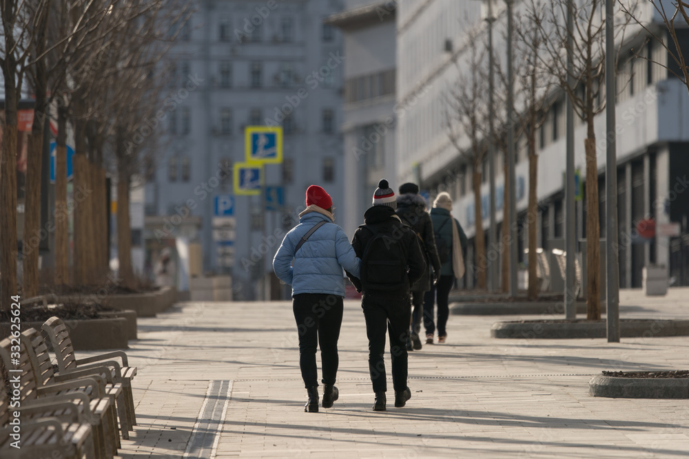 People on the Moscow street in the spring time. Couple of young man and woman walking. Coronavirus Pandemic lifestyle of the big city