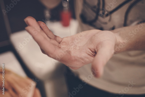 man squeezes antibacterial soap on his hand . protection from viruses and germs