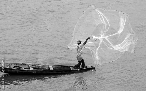 African Fisherman in wooden boat throwing out fishing net