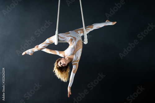 A young girl performs the acrobatic elements in the air trapeze. Studio shooting performances on a black background photo