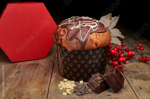 Traditional Italian Christmas cake from Milan: handmade panettone with chocolate glaze, components on view on rustic wooden table and decorations. photo