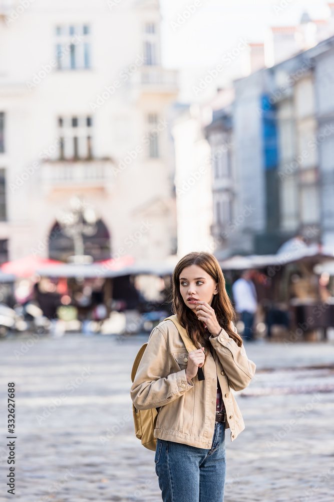 Fototapeta premium Beautiful woman looking away with backpack in city