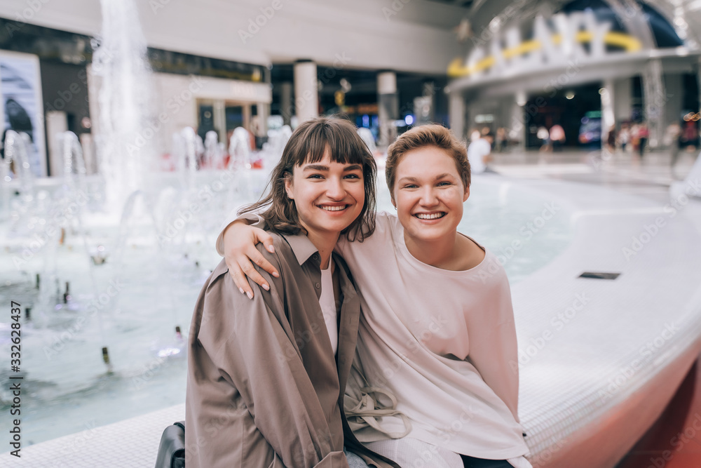 Two girls have fun in the mall, a fountain in the background Two girls have fun in the mall, a fountain in the background