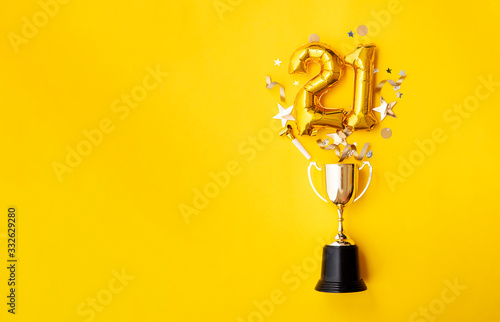Number 21 gold anniversary celebration balloon exploding from a winning trophy
