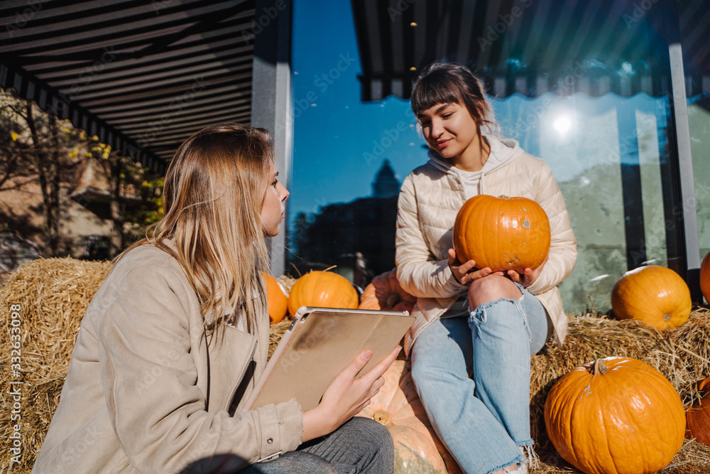 Girls have fun among pumpkins and haystacks on a city street