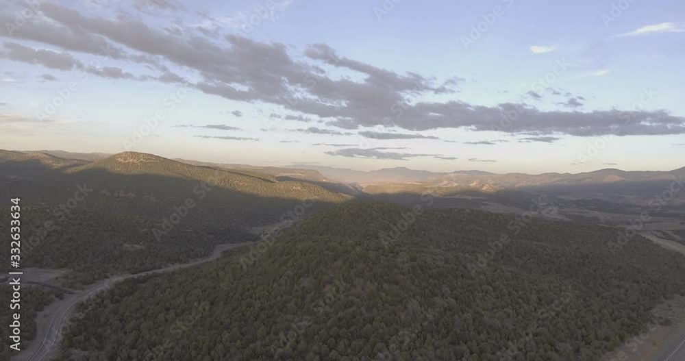 Flying over low mountainous terrain toward partially clouded distant sky, with railroad tracks snaking through trees and hills. Flying over low mountainous terrain toward partially clouded distant sky, with railroad tracks snaking through trees and hills.