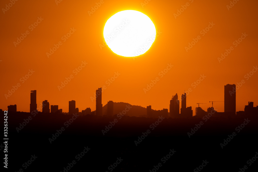 Sunset with big sun over Benidorm city skyline with text space