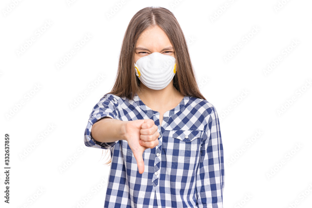 Concept of coronavirus quarantine. COVID-19. Child wearing medical protective face mask to health protection from influenza virus, isolated on white background. Teen girl giving thumb down gesture. Concept of coronavirus quarantine. COVID-19. Child wearing medical protective face mask to health protection from influenza virus, isolated on white background. Teen girl giving thumb down gesture.