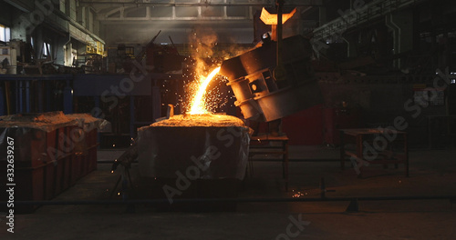 Smelting metal in a metallurgical plant. Liquid iron from metal ladle pouring in castings at factory photo