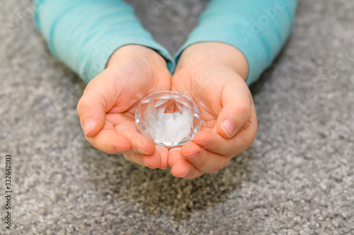 Close-up of the cupped hands of a five year old boy holding a big glass diamond
