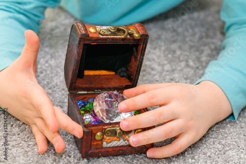Five year old boy playing with a treasure chest full of multicolored gems
