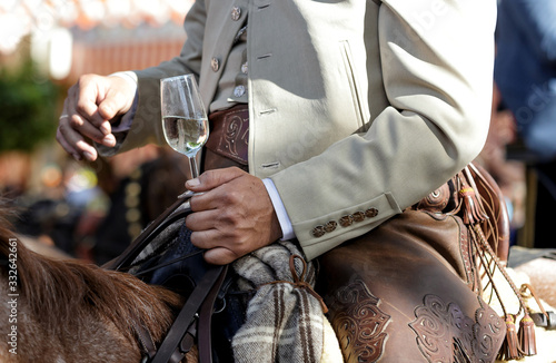 Rider on horseback dressed in traditional costume and holding glass of fino sherry (manzanilla sherry) at the April Fair (Feria de Abril) Andalusia, Spain. Travel and tourism concepts photo
