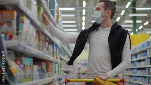 shopping at supermarket during coronavirus pandemic, man with mask on face photo