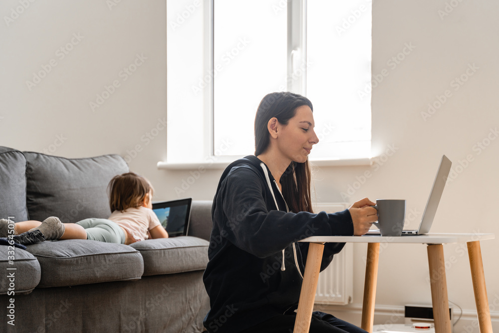 Young woman working from home. Child watching cartoons on the tablet. Work from home Young woman working from home. Child watching cartoons on the tablet. Work from home
