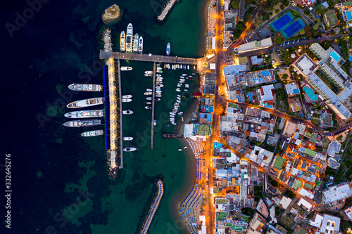 Aerial Drone top down photo of boats docked in a harbour. and street lights opened at sunset time