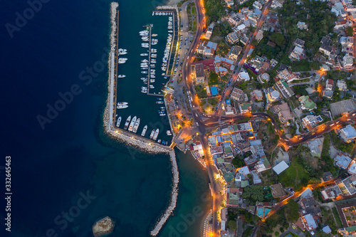 Aerial Drone top down photo of boats docked in a harbour. and street lights opened at sunset time