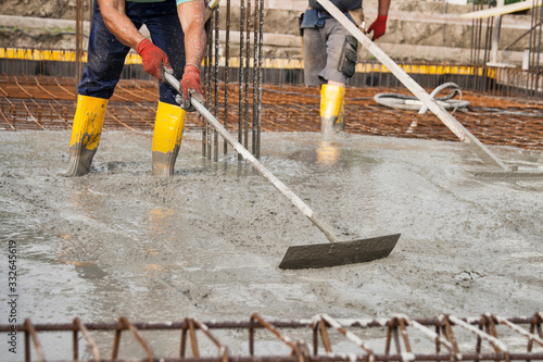 Fotografie bricklayers who level the freshly poured concrete to lay the foundations of a building