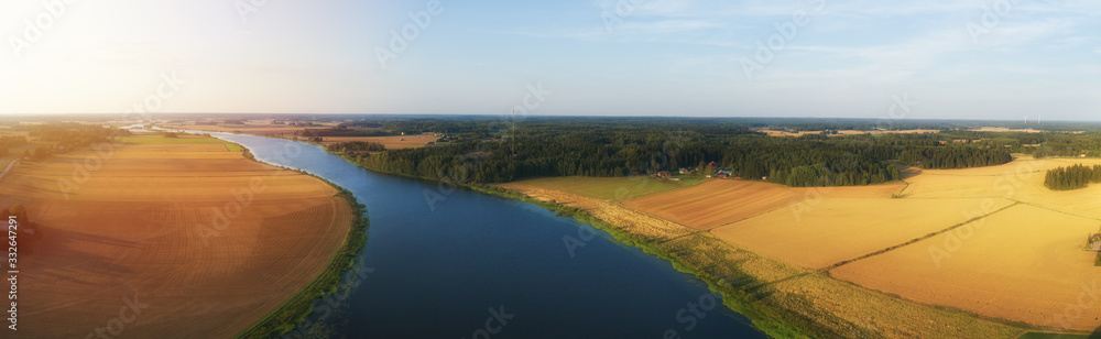 Rural aerial view of agriculture fields, meadows and beautiful river at sunset in Finland. View of fields before harvest at autumn.