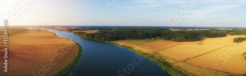 Rural aerial view of agriculture fields, meadows and beautiful river at sunset in Finland. View of fields before harvest at autumn.