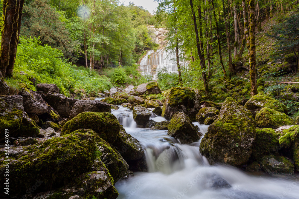 River flowing quickly in forest area, many mossy stones. Waterfall in back. France, Europe.. River flowing quickly in forest area, many mossy stones. Waterfall in back. France, Europe..