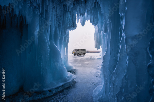 Russian local van on Baikal frozen lake in front of ice cave, Baikal in winter, Siberia, Russia photo