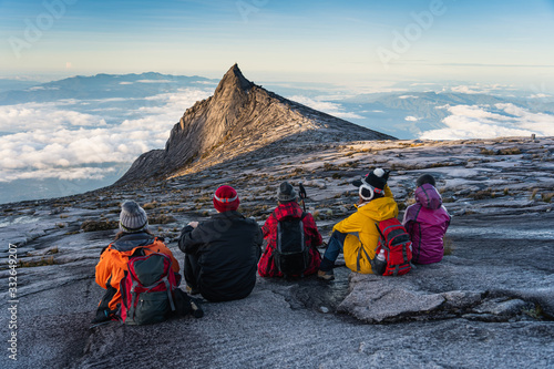 Trekkers sitting on rock looking to South peak, Kinabalu national park in Borneo island, Sabah state in Malaysia