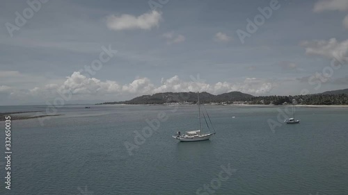 Drone flies around large Yacht in pretty harbour