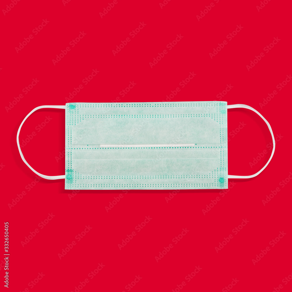 Medical face mask on a red background. The concept of a warning sign against the epidemic of the virus, coronovirus. Medical face mask on a red background. The concept of a warning sign against the epidemic of the virus, coronovirus.