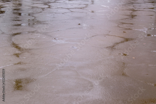 Surface of the lake is covered with ice. Crust areas with seams filled with water. Chatelle color, Violet hue. Light flare.