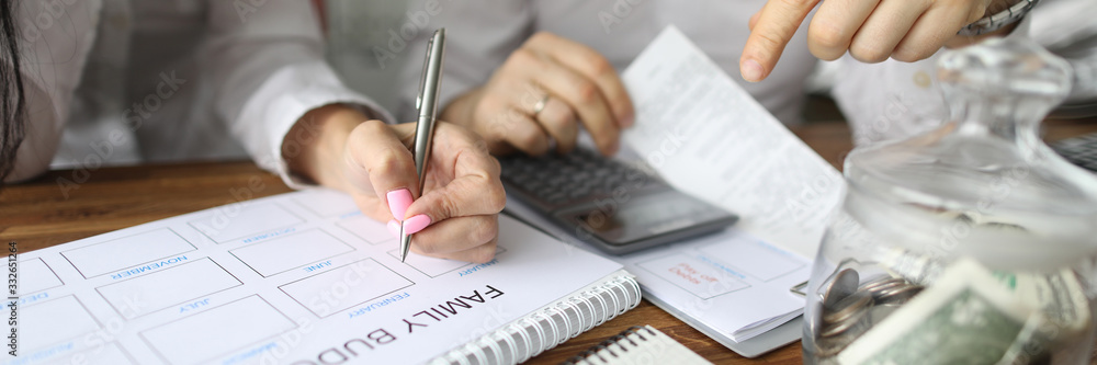 Close-up view of couple calculating family budget for new year. Spouse accounting expenses and planning future fund. Piggy-bank and calculator on table. Finance concept Close-up view of couple calculating family budget for new year. Spouse accounting expenses and planning future fund. Piggy-bank and calculator on table. Finance concept