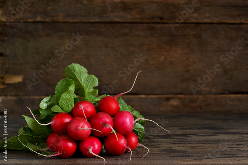 Fresh, young radish on a wooden background with space under the text. Top view.