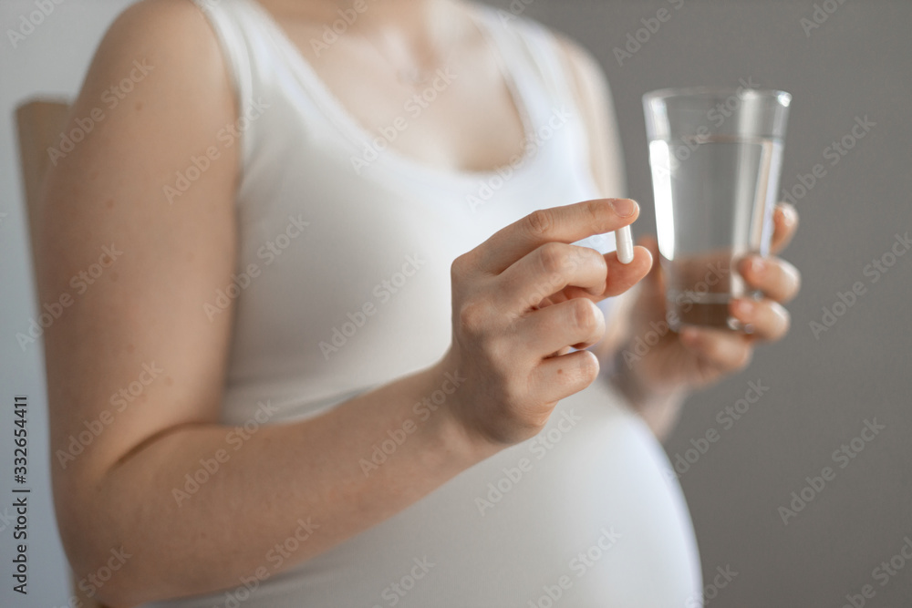 pregnant woman with white capsule between fingers pregnant woman with white capsule between fingers