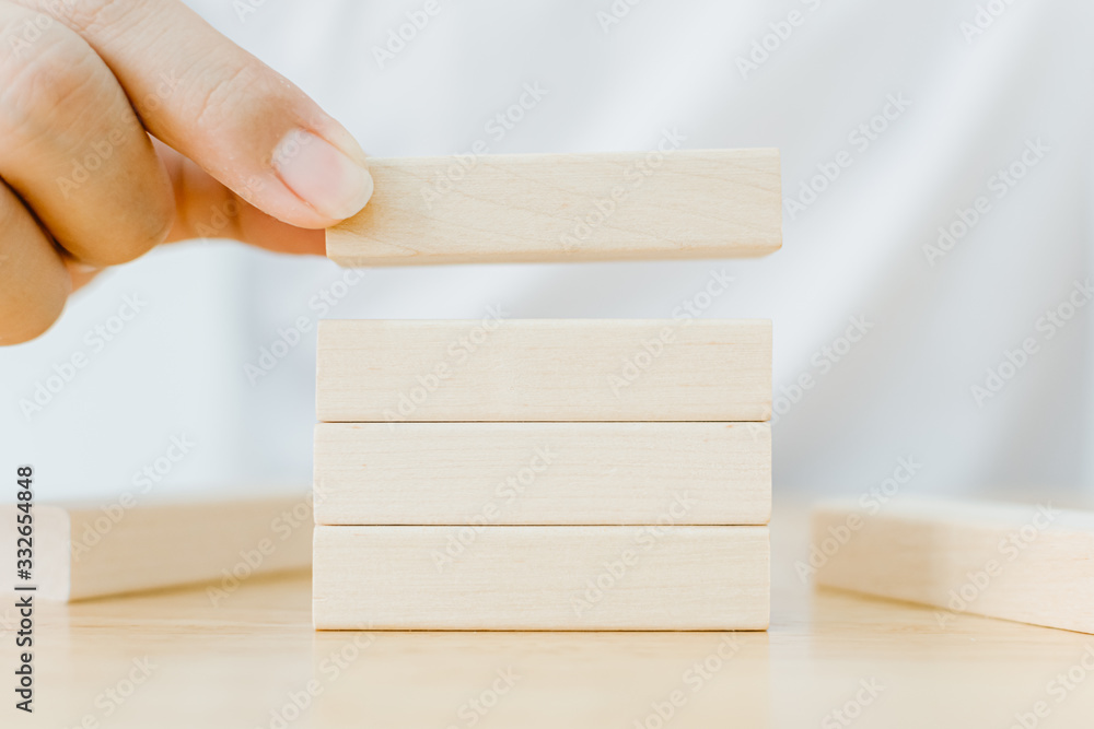 Hand arranging wood block stacking on top with wooden table. Business concept for growth success process