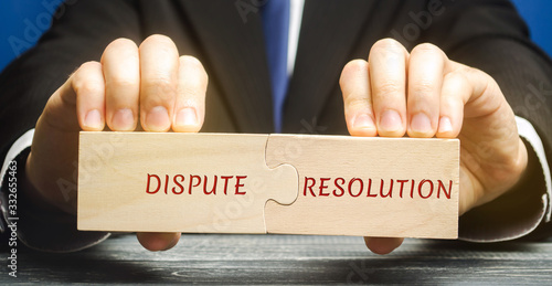 Konstfotografi Man holds wooden puzzles with the words Dispute Resolution