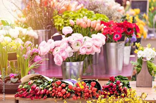 Colorful showcase in a florist store. Flowers in big vases. Bouquet of the Flower of Ranculus (pion rose) pink color, red anemones and tulips. Flower business