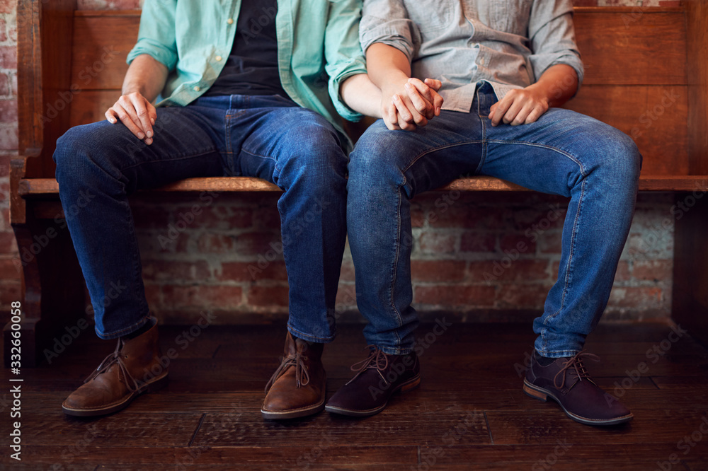 Close Up On Feet Of Same Sex Male Couple Holding Hands Sitting On Bench Together Close Up On Feet Of Same Sex Male Couple Holding Hands Sitting On Bench Together