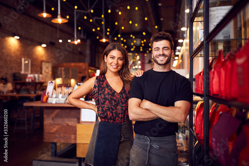 Portrait Of Male And Female Coffee Shop Owners Standing At Sales Desk