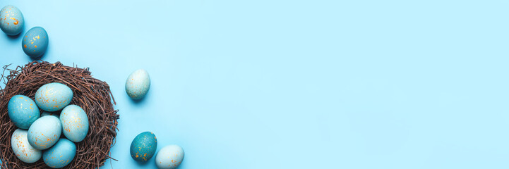 Easter eggs in nest on blue background. Flat lay, top view.