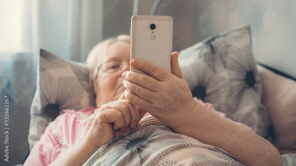 Coronavirus self-isolation advice for over-70s Elders, social isolation and loneliness in older people. Age-group risk for coronavirus. Lonely elderly woman lies in bed at home. - obrazy, fototapety, plakaty 