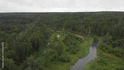 aerial view of the river in dark green forest on a rainy day in summer