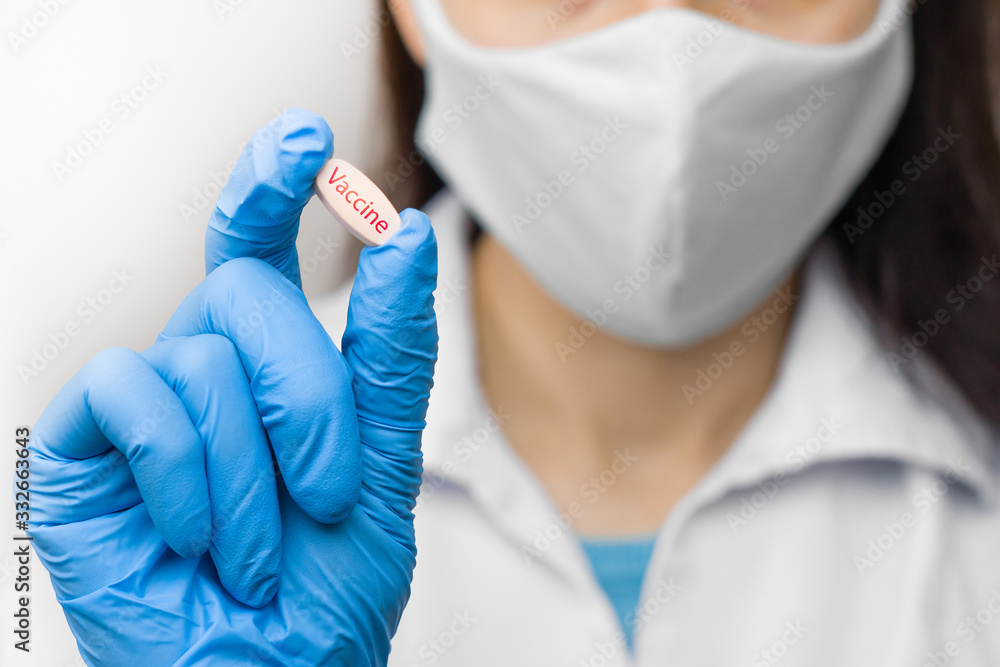 Fototapeta premium A pill in hand in blue gloves. Female is holding a vaccine against coronavirus,2019-nCoV, SARS-nCov, COVID-2019 outbreaking.