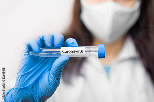 Test tube with vaccine against coronavirus, 2019-nCoV, SARS-nCov, COVID-19 in scientist hand wearing protective mask and blue gloves.