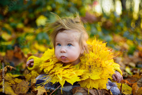 happy little girl laughs and plays outdoors. On the neck there is a necklace of autumn leaves.