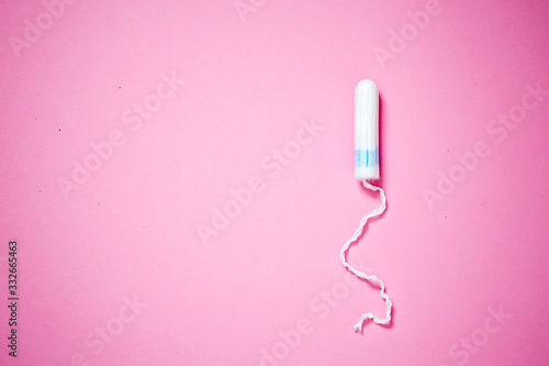 Medical female tampon on a pink background with copy space. Hygienic white tampon for women. Cotton swab. Menstruation, means of protection. photo