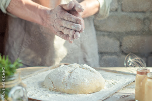 Baker man holds hands over the bread from whole wheat flour rustic style