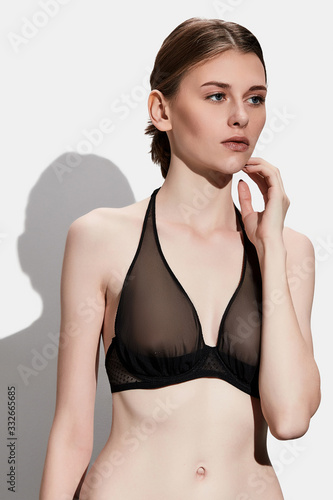 фотографія A young lady with wheat-coloured hair is wearing a black bra with soft underwired cups and a neck strap