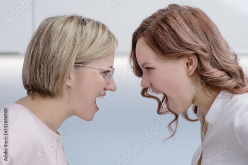 Mom and her teen daughter shout at each other forehead. Relationship problems, transitional period